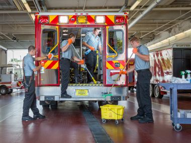 Fire crew manually cleaning an ambulance.